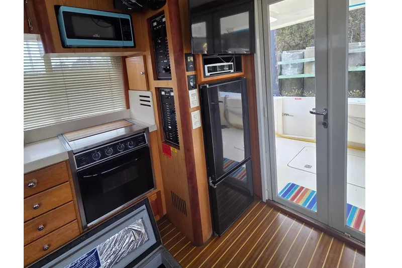 Slide: The Image of 2006 Mainship 40 Trawler kitchen with oven, microwave, and outdoor access. - 10