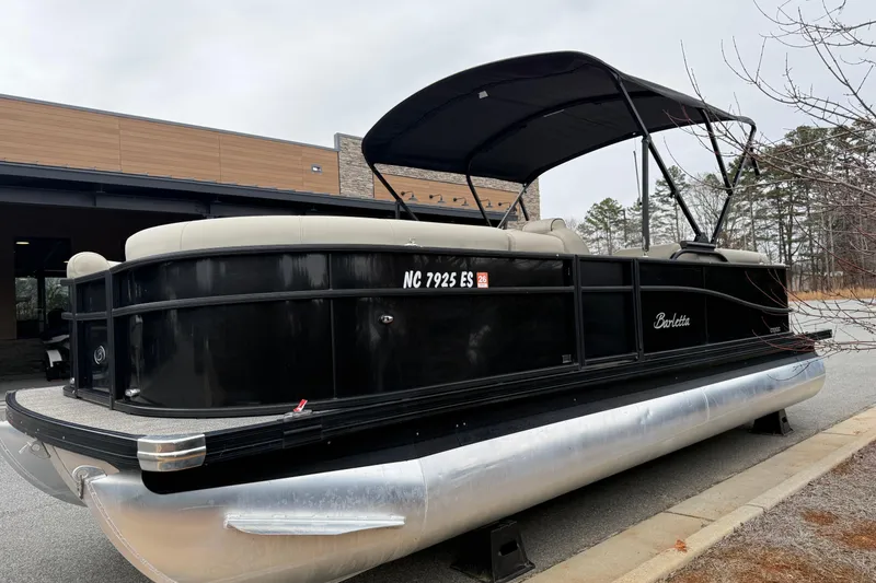 Slide: The Image of 2021 Barletta C22QC pontoon boat with black exterior and canopy, parked outdoors. - 20