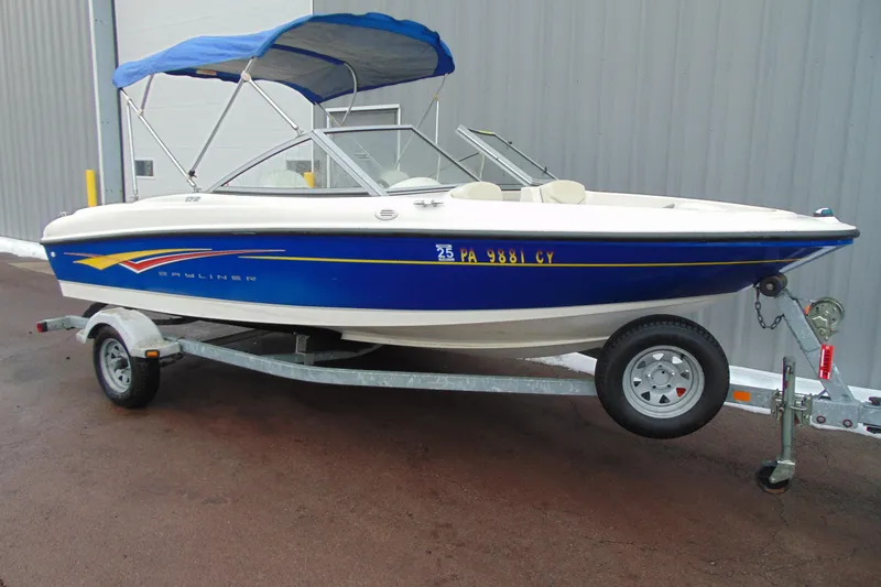 The Image of 2007 Bayliner 175 Bowrider boat with blue canopy on trailer, parked outdoors. - 2