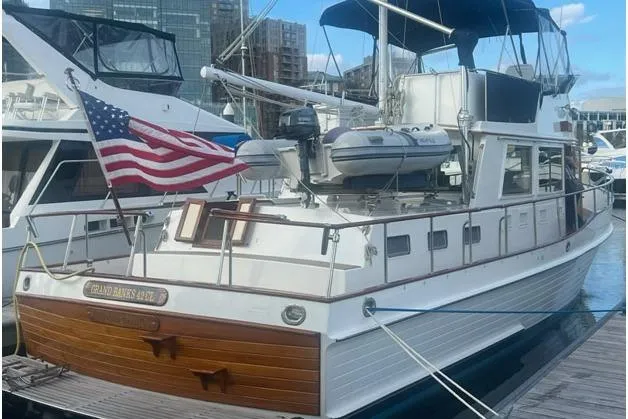 Slide: The Image of 2002 Grand Banks 42 Classic yacht docked, featuring American flag and tender on deck. - 1