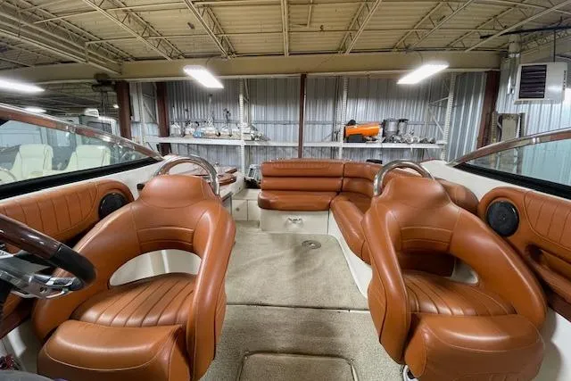 Slide: The Image of 2006 Doral 265 Elite Bowrider interior with brown leather seats in a warehouse setting. - 10