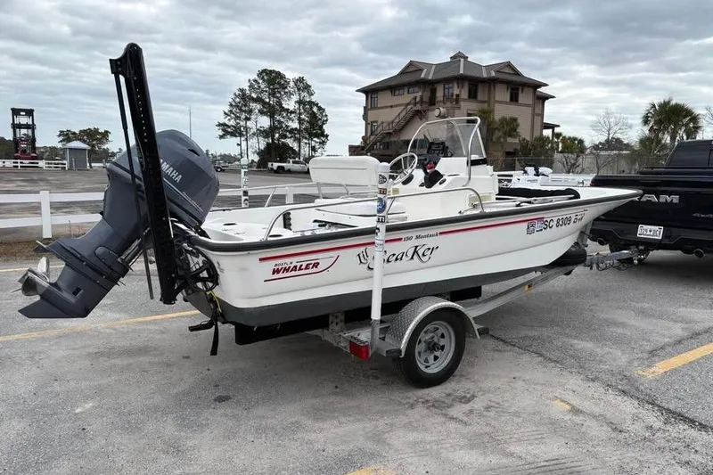 Slide: The Image of 2007 Boston Whaler 150 Montauk boat on trailer, parked outdoors near a house. - 5