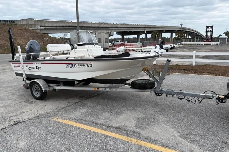 Slide: The Image of 2007 Boston Whaler 150 Montauk boat on trailer in parking lot near bridge. - 7