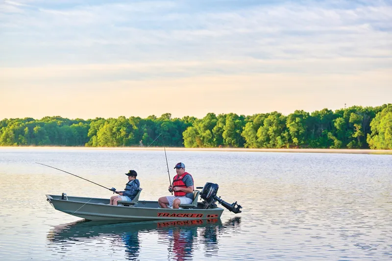 Slide: The Image of Two people fishing on a 2026 Tracker Grizzly 12 Jon boat in a serene lake. - 7