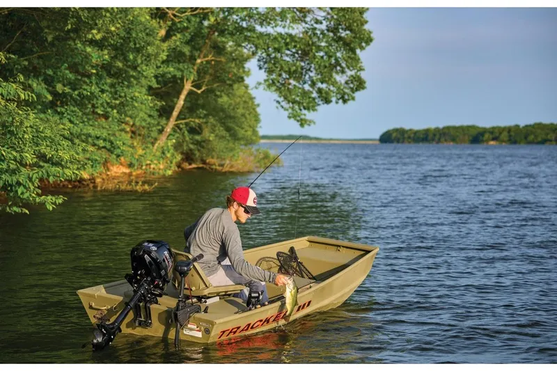 Slide: The Image of Man fishing on a 2026 Tracker Grizzly 12 Jon boat in a scenic lake. - 8