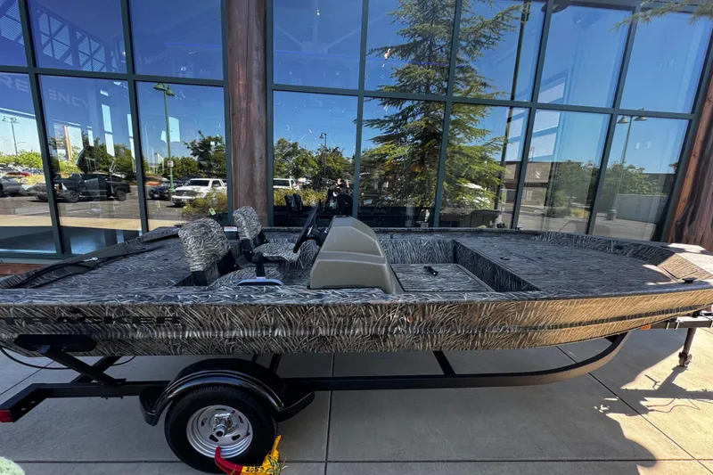 The Image of 2026 Tracker Grizzly 1754 SC boat with camouflage design on display outside a showroom. - 0