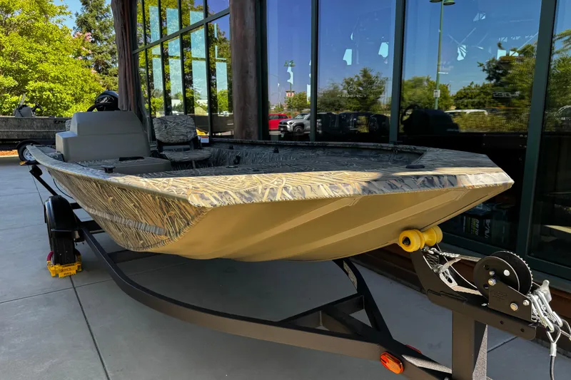 Slide: The Image of 2026 Tracker Grizzly 1754 SC boat on trailer, parked outdoors near glass building. - 2