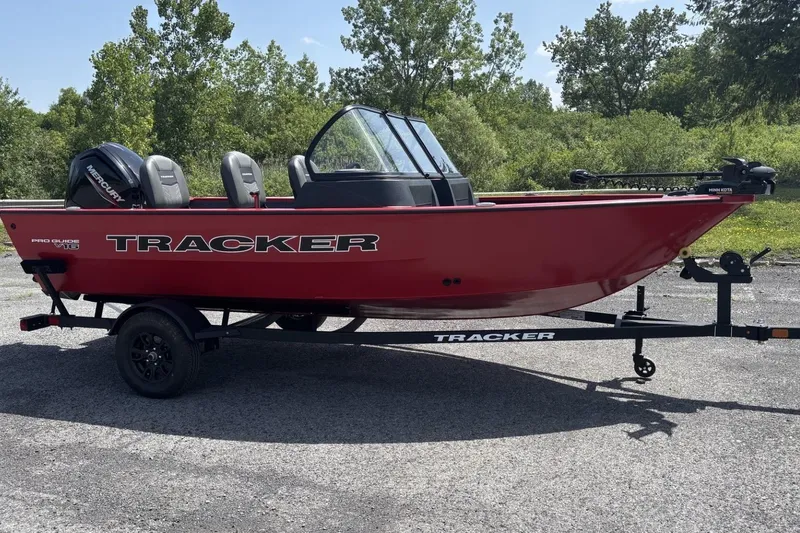 Slide: The Image of 2026 Tracker Pro Guide V-16 SC boat in vibrant red on a trailer, parked outdoors. - 2