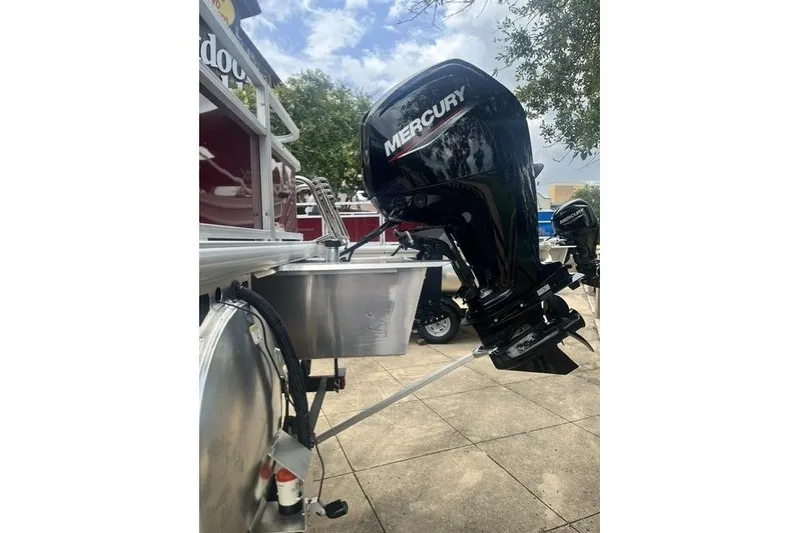 Slide: The Image of 2026 Sun Tracker Bass Buggy 18 DLX with Mercury outboard motor, parked outdoors. - 7