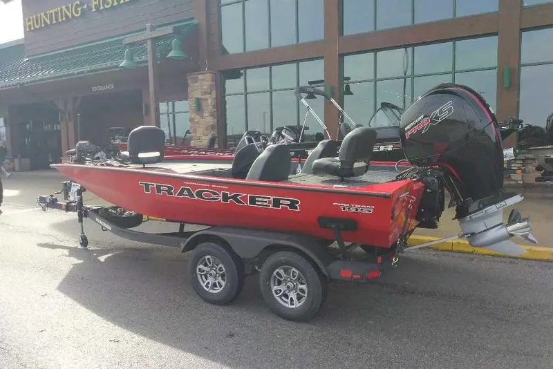 The Image of 2026 Tracker Pro Team 195 boat with Mercury engine, parked outside a hunting and fishing store. - 0