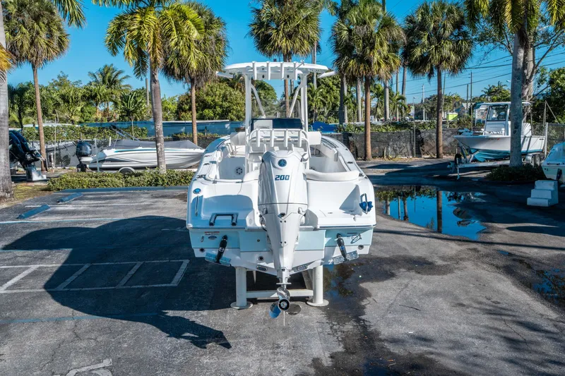 Slide: The Image of 2026 Sea Hunt Ultra 229 boat on parking lot with palm trees. - 2
