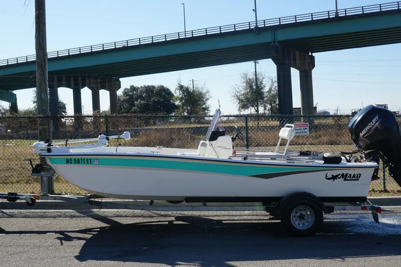 Slide: The Image of 2021 Mako Pro Skiff 17 CC boat on trailer near bridge. - 2
