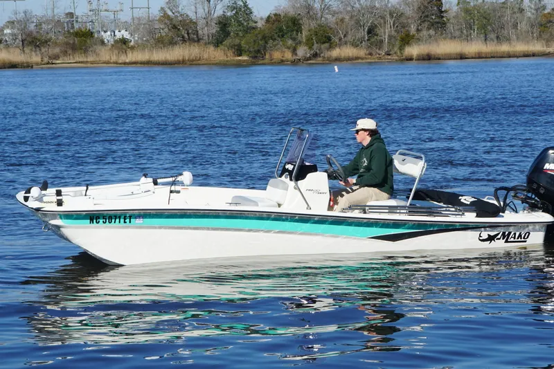 Slide: The Image of 2021 Mako Pro Skiff 17 CC boat on calm water, person steering. - 7