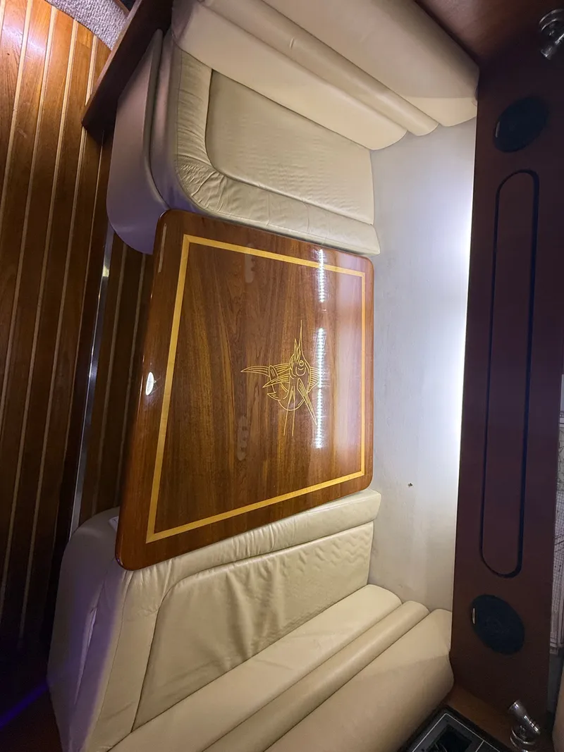 Slide: The Image of Interior of a 2003 Pursuit 3400 Express with wooden table and leather seats. - 12