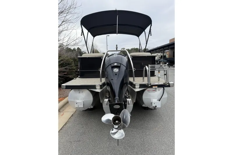 Slide: The Image of 2021 Barletta C22QC pontoon boat with outboard motor and canopy, parked on pavement. - 19