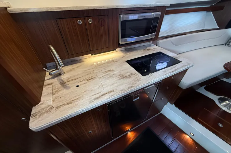 Slide: The Image of Luxurious interior of 2019 Pursuit OS 355 Offshore with polished wooden table and cushioned seating. - 26