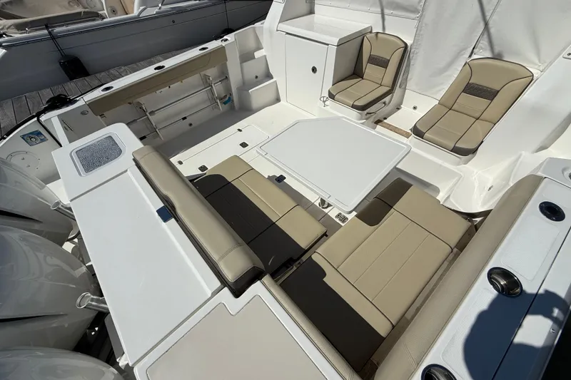 Slide: The Image of 2019 Pursuit OS 355 Offshore boat interior with seating and table, docked at marina. - 5