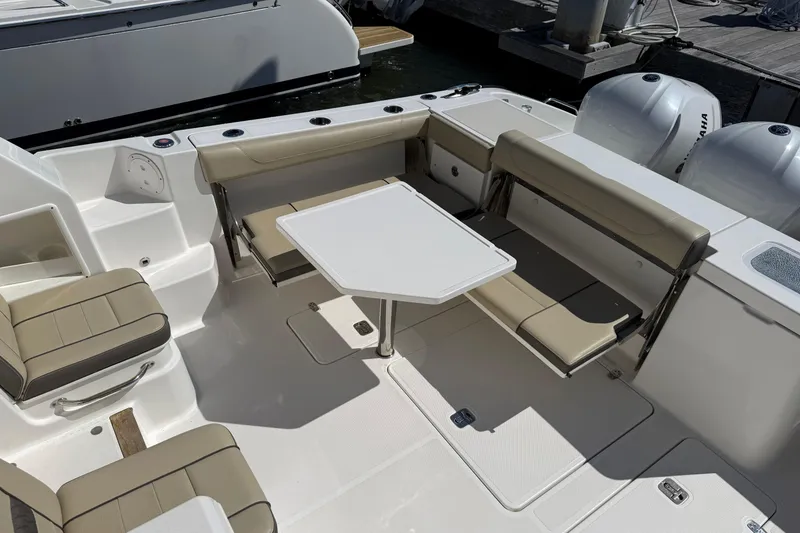 Slide: The Image of 2019 Pursuit OS 355 Offshore boat interior with seating, table, and triple outboard engines. - 6