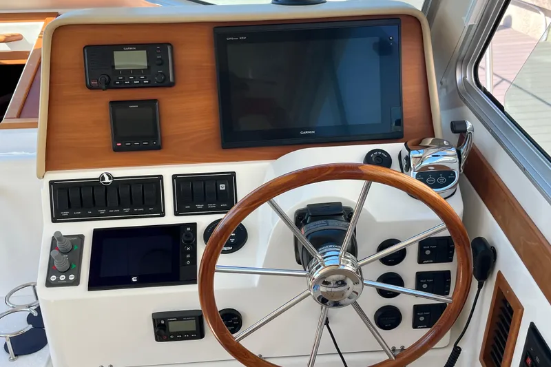 Slide: The Image of 2017 Back Cove 37 helm with Garmin navigation, wooden steering wheel, and control panel. - 12