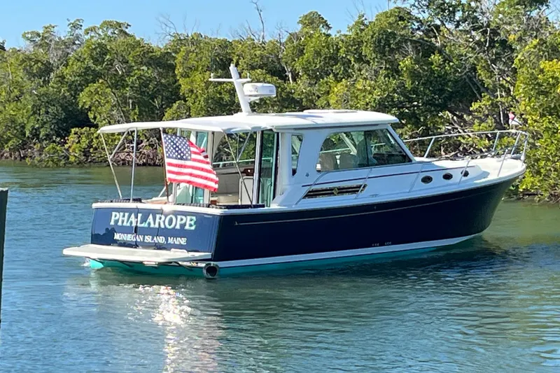 Slide: The Image of 2017 Back Cove 37 boat named "Phalarope" on water, American flag, lush greenery background. - 4