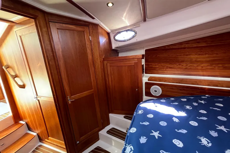 Slide: The Image of 2017 Back Cove 37 cabin interior with wooden finish and nautical-themed bedding. - 7
