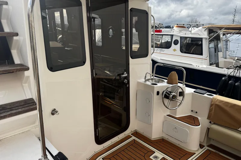 Slide: The Image of 2023 Ranger Tug R-31 CB boat interior with helm and wooden deck. - 10