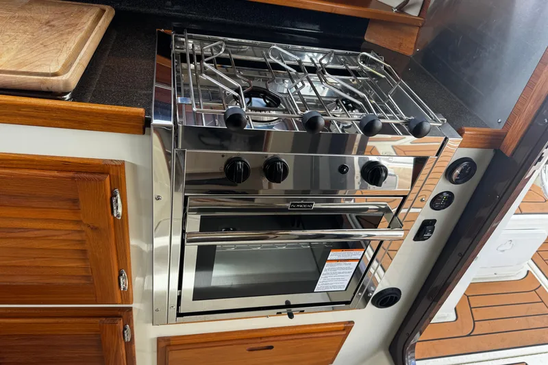 Slide: The Image of 2023 Ranger Tug R-31 CB kitchen with stainless steel stove and wooden cabinetry. - 14