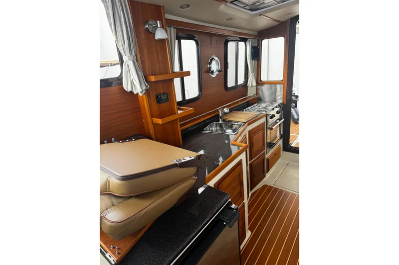 Slide: The Image of 2023 Ranger Tug R-31 CB interior with wood finish, kitchenette, and seating area. - 23
