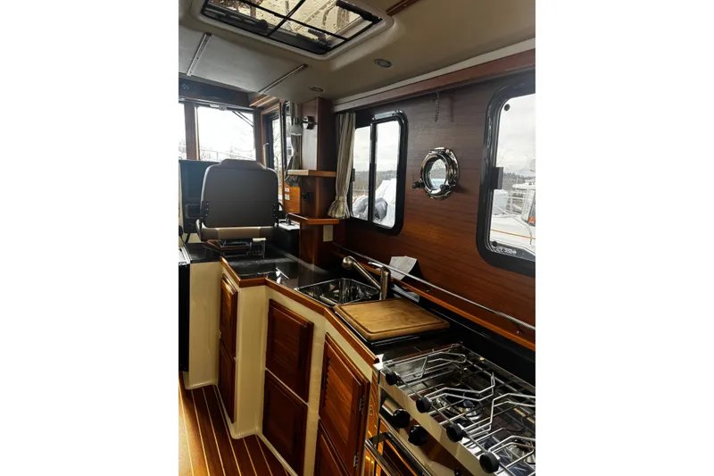 Slide: The Image of Interior of 2023 Ranger Tug R-31 CB, featuring a modern kitchen with wood accents. - 24