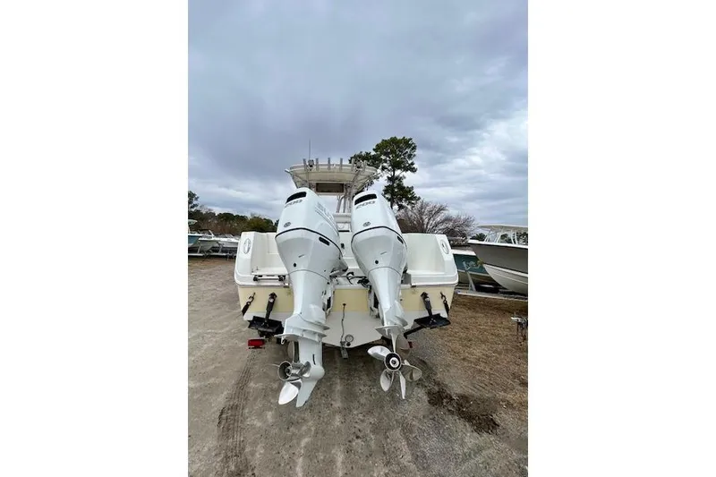 Slide: The Image of 2005 Sailfish 266 CC boat with dual outboard motors, parked on a gravel surface. - 4