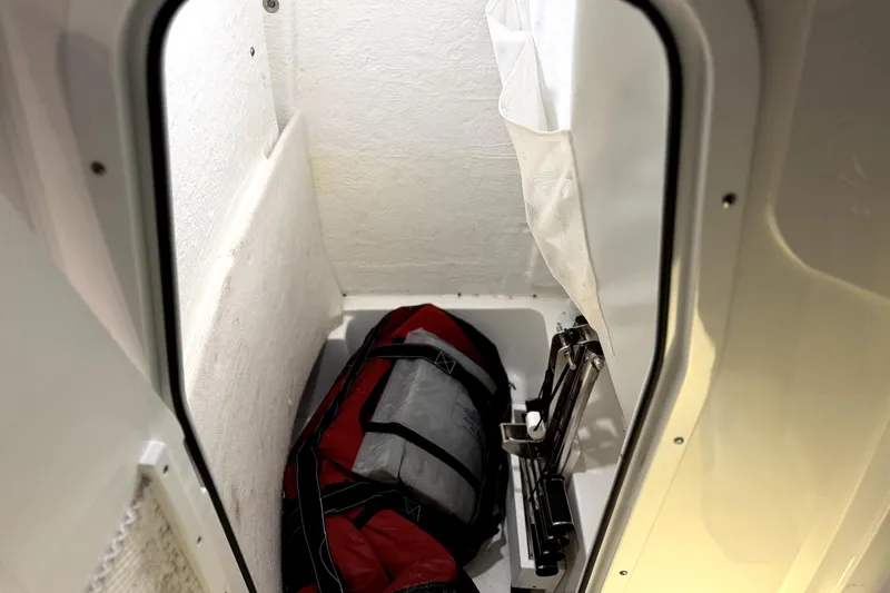 Slide: The Image of 2024 Sea Hunt Ultra 239 SE storage compartment with red and black bag inside. - 19