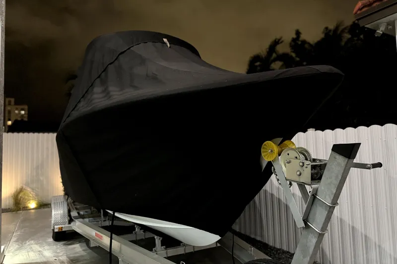 Slide: The Image of 2024 Sea Hunt Ultra 239 SE boat covered on trailer at night. - 3