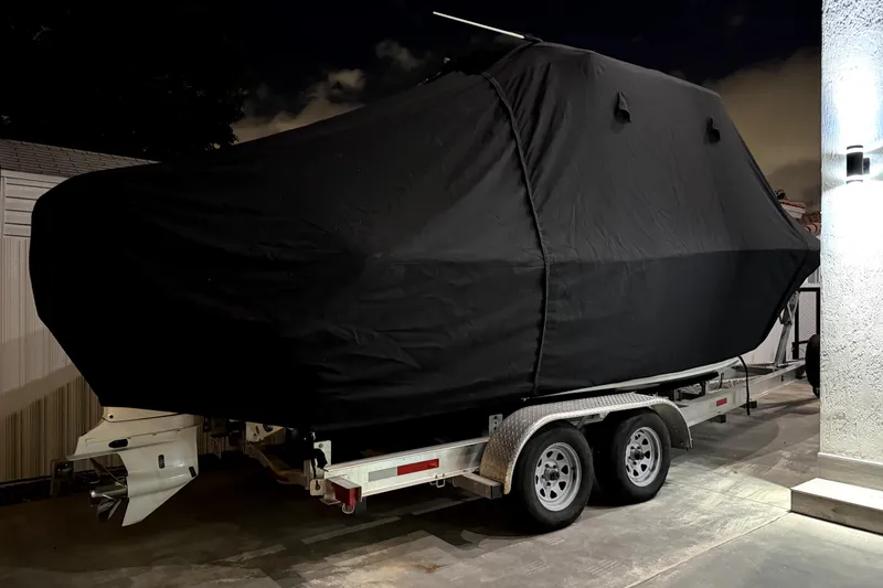 Slide: The Image of 2024 Sea Hunt Ultra 239 SE boat covered on a trailer at night. - 4