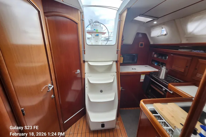 Slide: The Image of Interior of 2005 Beneteau Oceanis Clipper 393 sailboat, featuring kitchen and wooden cabinetry. - 5