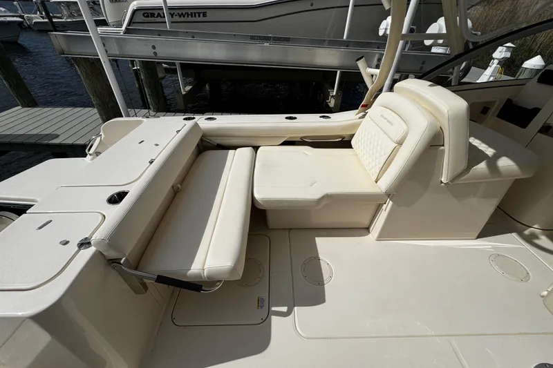 Slide: The Image of 2026 Grady-White Freedom 235 boat interior with beige seating and cup holders. - 18