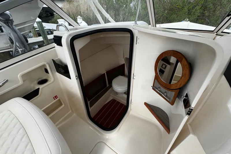 Slide: The Image of Interior of 2026 Grady-White Freedom 235 boat, featuring a compact cabin with a toilet. - 33
