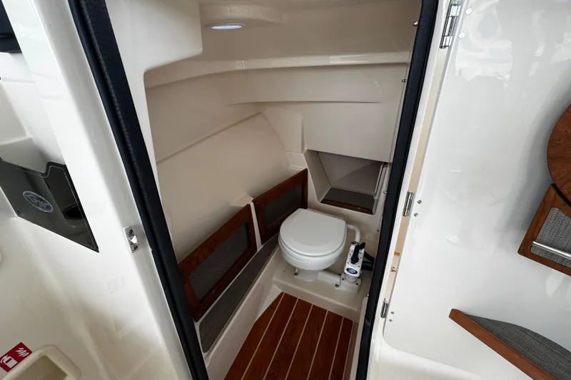 Slide: The Image of 2026 Grady-White Freedom 235 boat interior with compact marine toilet and wooden accents. - 34