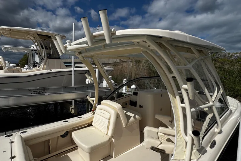 Slide: The Image of 2026 Grady-White Freedom 235 boat with seating and rod holders, docked under cloudy skies. - 44