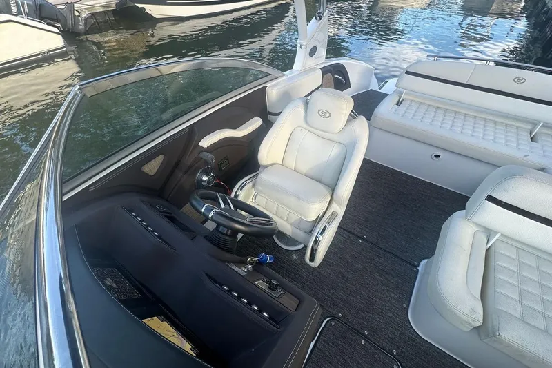 Slide: The Image of 2021 Cobalt R3 boat interior with white seating and steering wheel, docked on calm water. - 16