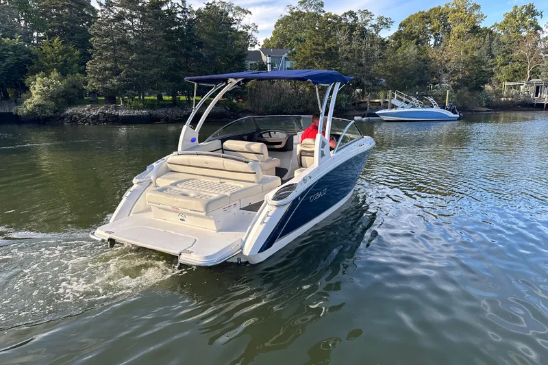 Slide: The Image of 2021 Cobalt R3 boat cruising on a serene lake with lush greenery. - 2