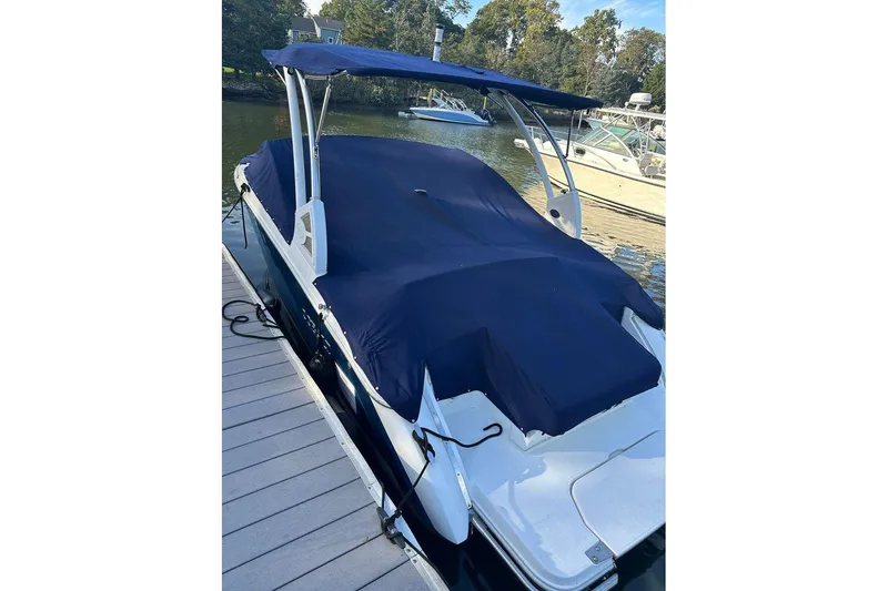 Slide: The Image of 2021 Cobalt R3 boat docked, covered with a blue tarp, surrounded by water and trees. - 25