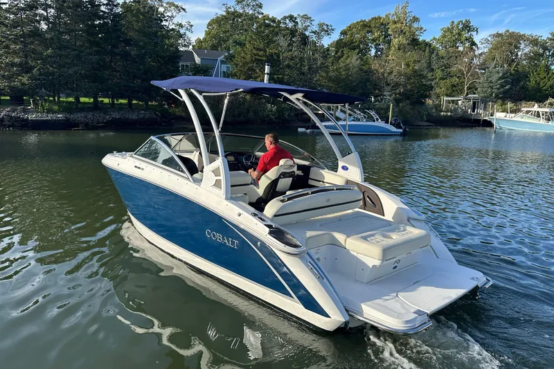 Slide: The Image of 2021 Cobalt R3 boat cruising on a calm river with lush greenery. - 5