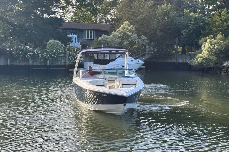 Slide: The Image of 2021 Cobalt R3 boat cruising on a calm river near a house with lush greenery. - 6