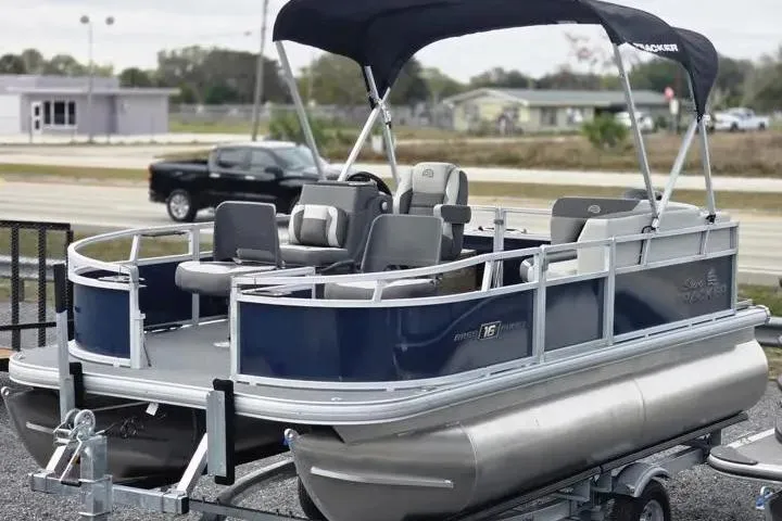 The Image of 2026 Sun Tracker Bass Buggy 16 XL Select pontoon boat on trailer, featuring canopy and seating. - 0