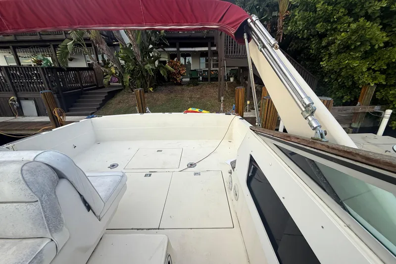 Slide: The Image of 1986 Chris-Craft 336 Commander boat with red canopy, docked near lush greenery. - 15