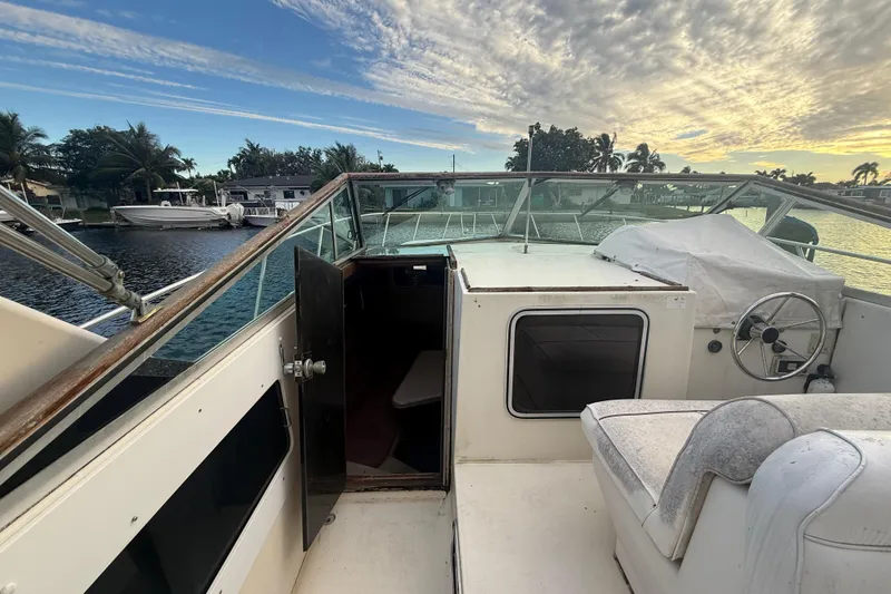 Slide: The Image of 1986 Chris-Craft 336 Commander boat interior with open cabin door, docked by waterfront homes. - 22