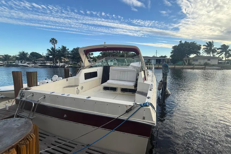 Slide: The Image of 1986 Chris-Craft 336 Commander docked by a scenic waterfront with palm trees. - 3
