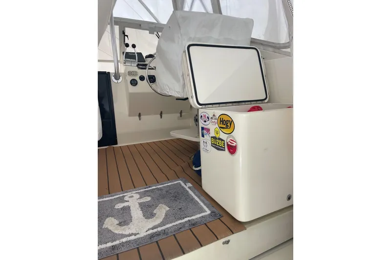 Slide: The Image of Interior of a 2004 Carolina Classic 28 boat with anchor-themed rug and sticker-covered cooler. - 10