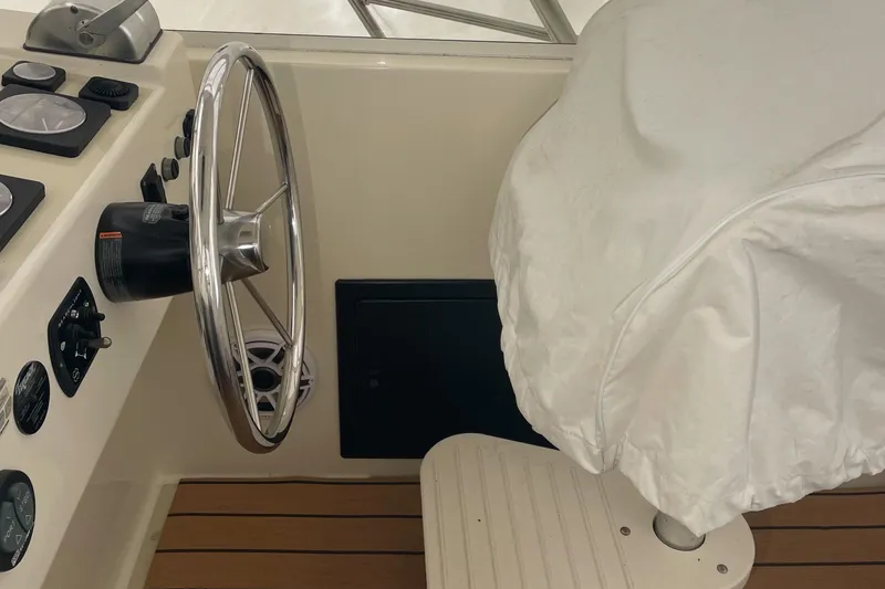 Slide: The Image of 2004 Carolina Classic 28 boat helm with steering wheel and covered seat. - 16