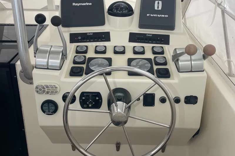 Slide: The Image of Control panel of a 2004 Carolina Classic 28 boat with steering wheel and navigation instruments. - 18